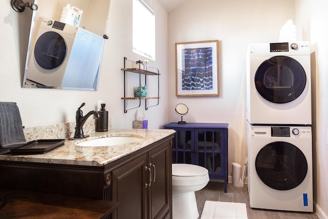 washroom with laundry area, wood finished floors, stacked washer / drying machine, and a sink