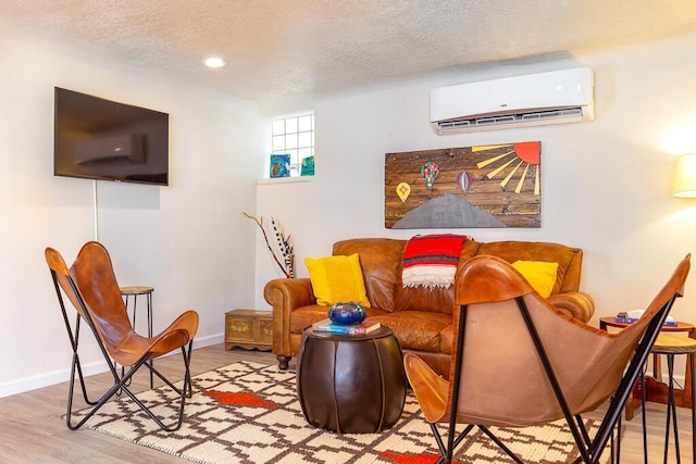 living area with a wall mounted AC, a textured ceiling, wood finished floors, recessed lighting, and baseboards