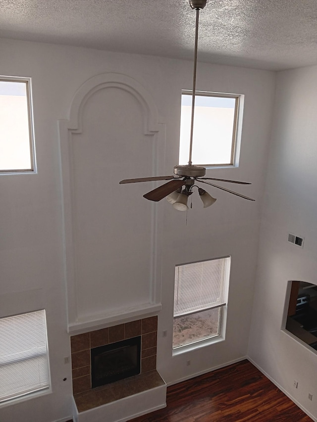 unfurnished living room with ceiling fan, visible vents, a healthy amount of sunlight, and dark wood-style floors