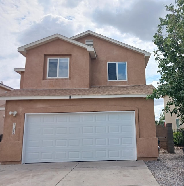 view of front of home with stucco siding, concrete driveway, a garage, and fence