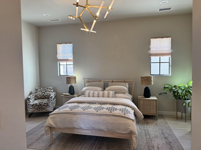 bedroom with a chandelier, visible vents, baseboards, and wood finished floors