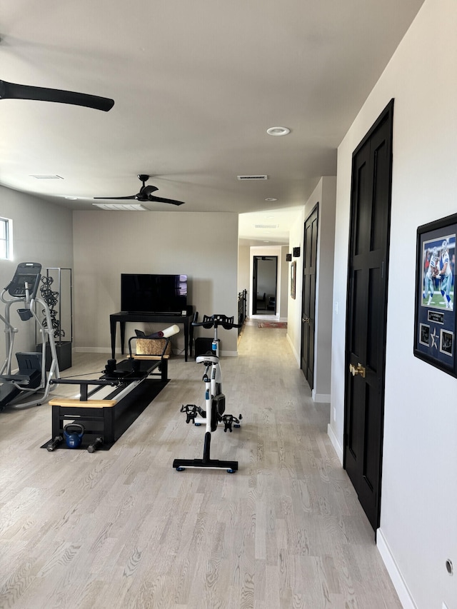 workout area with light wood-style flooring, baseboards, and ceiling fan