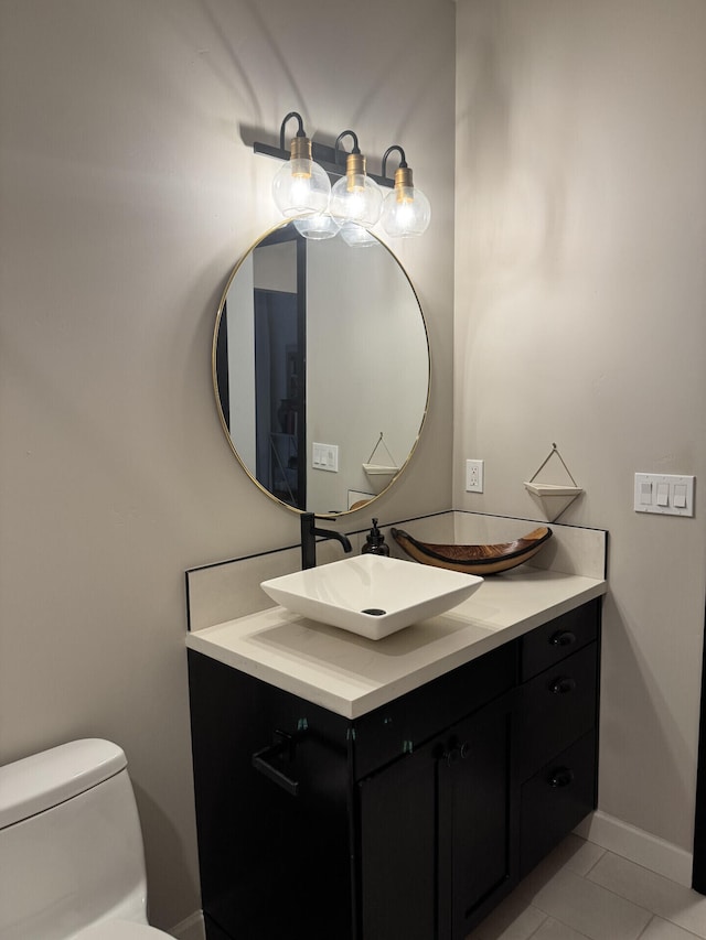 half bathroom featuring tile patterned floors, toilet, vanity, and baseboards