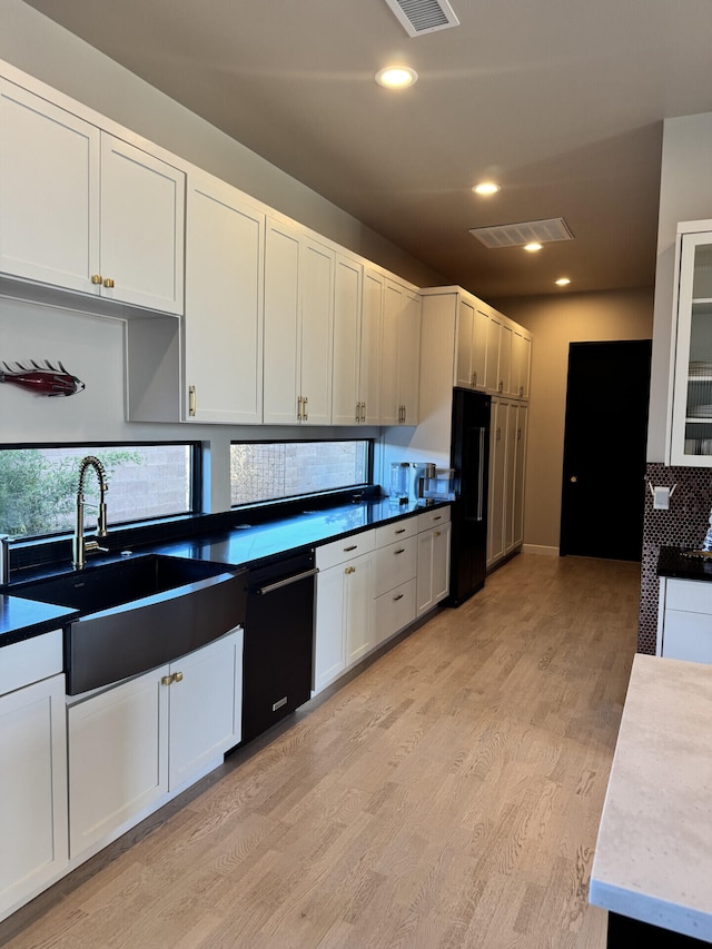 kitchen featuring visible vents, light wood finished floors, a sink, black appliances, and white cabinetry