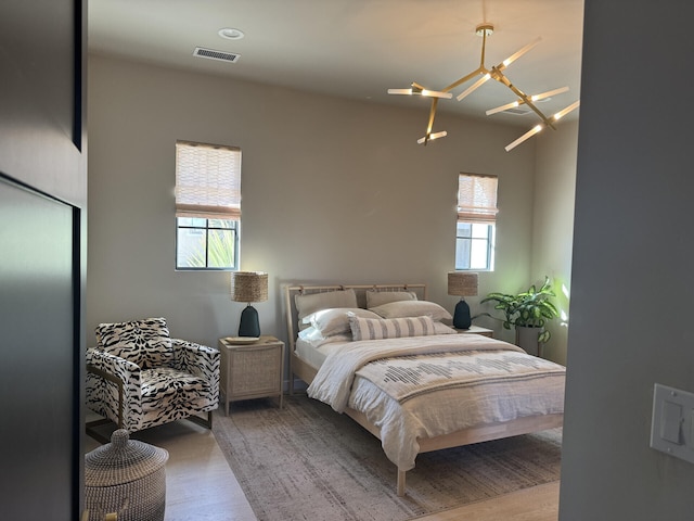 bedroom with visible vents, wood finished floors, and ceiling fan with notable chandelier