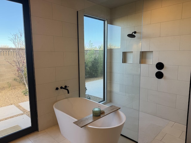 bathroom with tile patterned floors, a soaking tub, a walk in shower, and tile walls