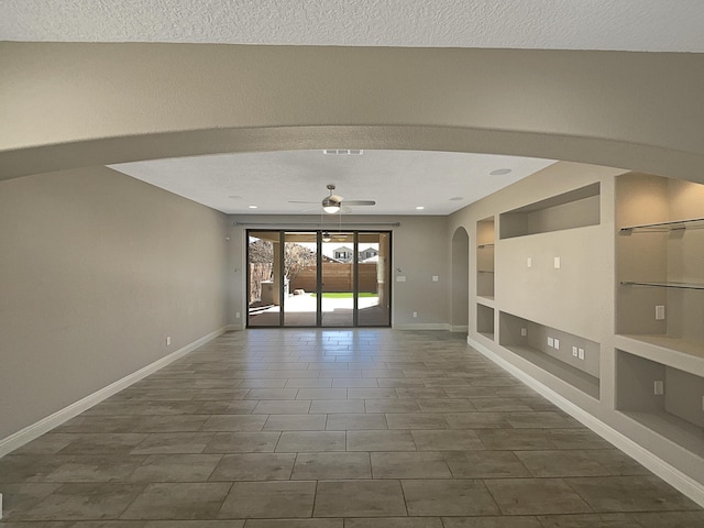 spare room with built in features, baseboards, a textured ceiling, and ceiling fan