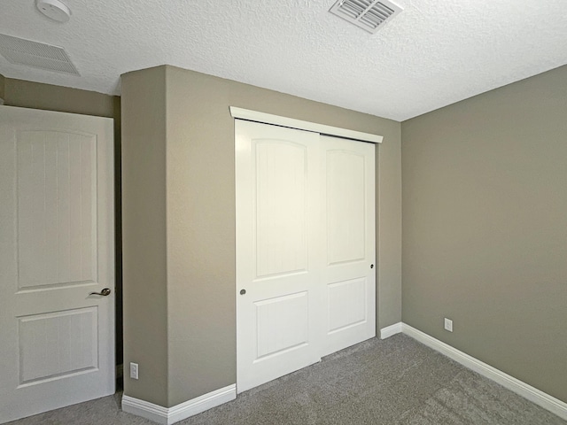 unfurnished bedroom featuring a closet, baseboards, visible vents, and dark carpet