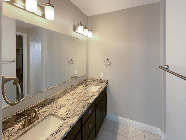 bathroom with double vanity, baseboards, marble finish floor, and a sink