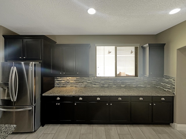 kitchen featuring backsplash, stone countertops, wood tiled floor, and stainless steel fridge with ice dispenser