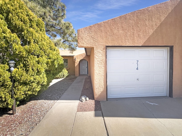 pueblo revival-style home featuring driveway and stucco siding