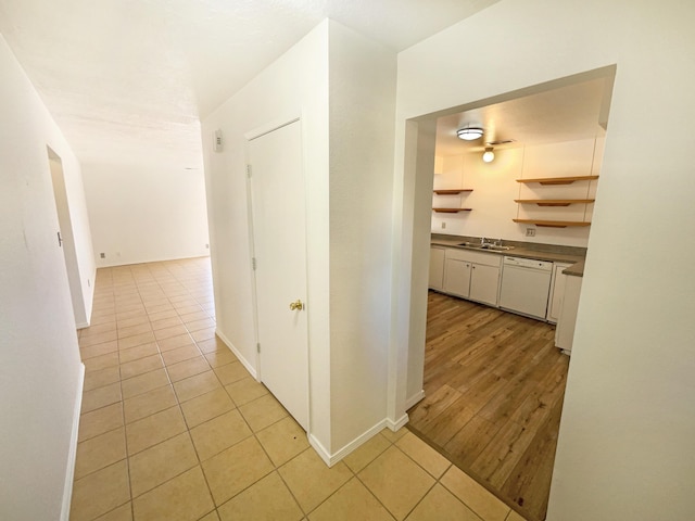 hallway with a sink, baseboards, and light tile patterned floors