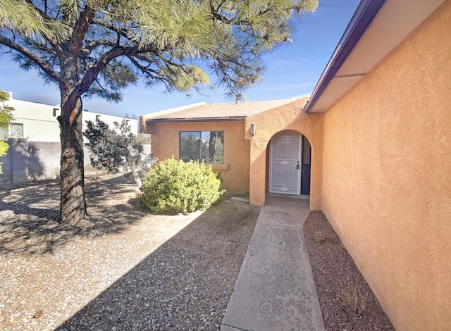 doorway to property featuring fence and stucco siding