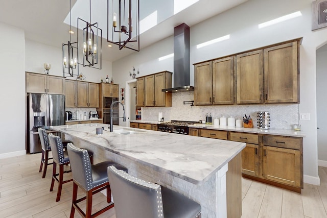 5721 Rio Animas Rd NE, Rio Rancho, NM 87144 - kitchen featuring stainless steel refrigerator with ice dispenser, a towering ceiling, wall chimney range hood, light wood-style flooring, and tasteful backsplash