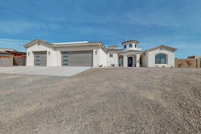 mediterranean / spanish home with a tile roof, concrete driveway, a garage, and fence