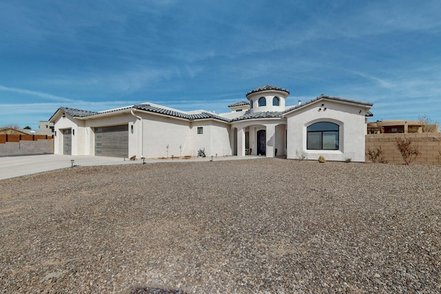 mediterranean / spanish house with stucco siding, a tiled roof, a garage, and fence