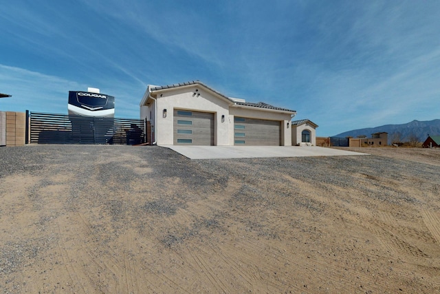 view of front facade featuring gravel driveway, fence, a tiled roof, stucco siding, and an attached garage