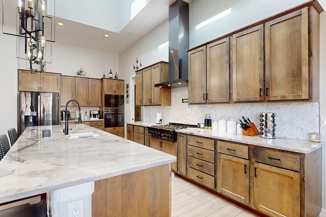 kitchen featuring extractor fan, a towering ceiling, stainless steel fridge, gas stovetop, and a sink