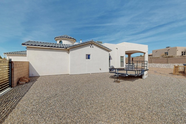 rear view of house featuring a patio, a tiled roof, fence, and stucco siding