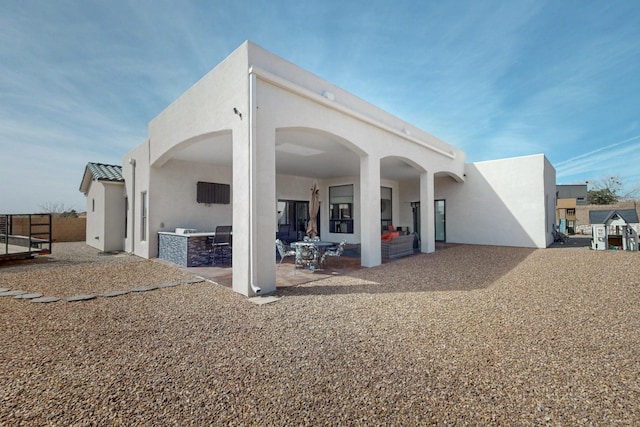 rear view of property featuring stucco siding and a patio area