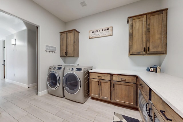 laundry area featuring washing machine and dryer, cabinet space, baseboards, and visible vents