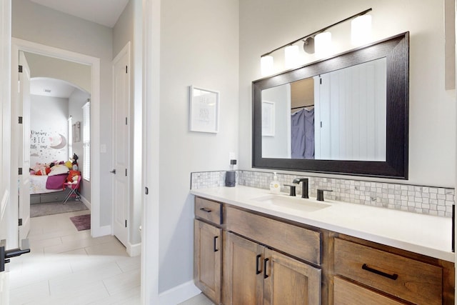 bathroom with tasteful backsplash, vanity, ensuite bathroom, and baseboards