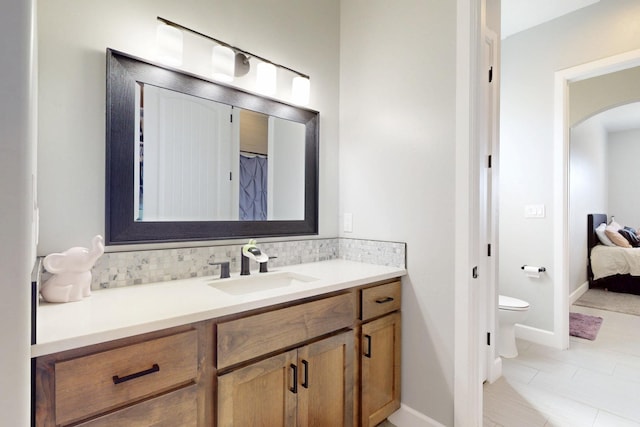 full bath featuring decorative backsplash, toilet, vanity, and baseboards