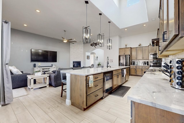 kitchen featuring light stone counters, a sink, open floor plan, stainless steel appliances, and arched walkways