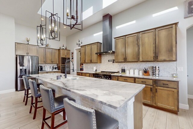 5721 Rio Animas Rd NE, Rio Rancho, NM 87144 - kitchen featuring stainless steel refrigerator with ice dispenser, a towering ceiling, wall chimney range hood, light wood-style flooring, and tasteful backsplash
