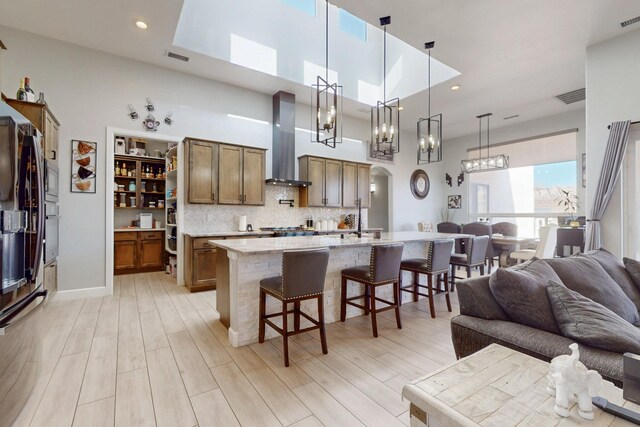 5721 Rio Animas Rd NE, Rio Rancho, NM 87144 - kitchen with wall chimney range hood, a chandelier, open floor plan, a kitchen bar, and a high ceiling