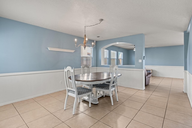 dining room featuring light tile patterned floors, a notable chandelier, and a textured ceiling