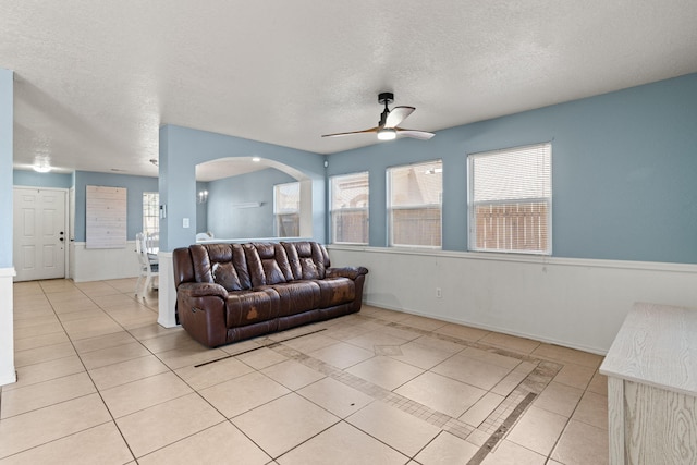 living area with light tile patterned flooring, arched walkways, and a textured ceiling