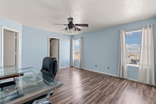 unfurnished office featuring wood finished floors, baseboards, visible vents, ceiling fan, and a textured ceiling