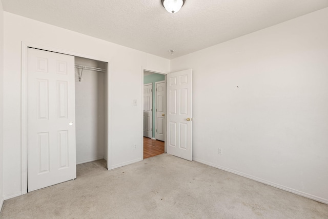 unfurnished bedroom featuring a closet, a textured ceiling, baseboards, and carpet floors