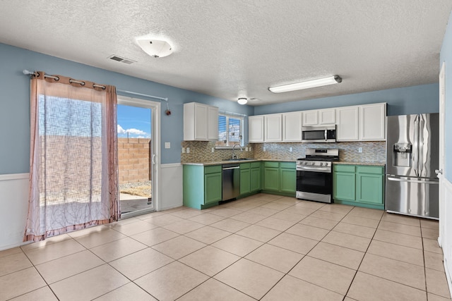 kitchen with visible vents, a sink, appliances with stainless steel finishes, white cabinets, and green cabinetry