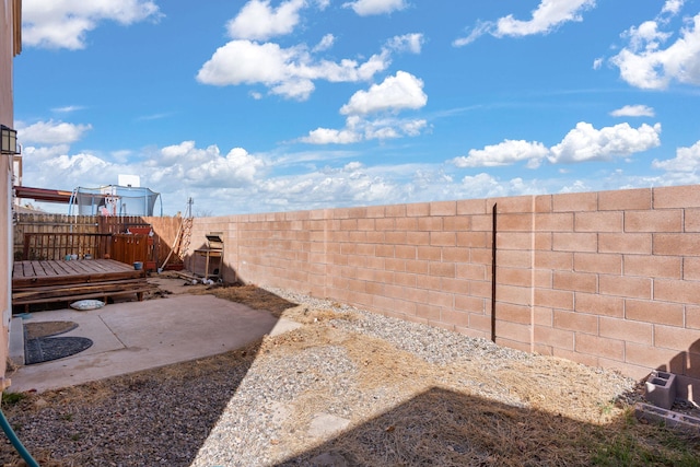 view of yard featuring a deck, a patio, and a fenced backyard