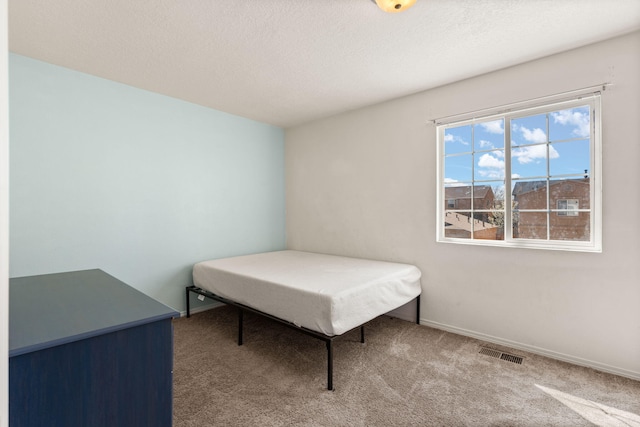 bedroom with visible vents, a textured ceiling, baseboards, and carpet