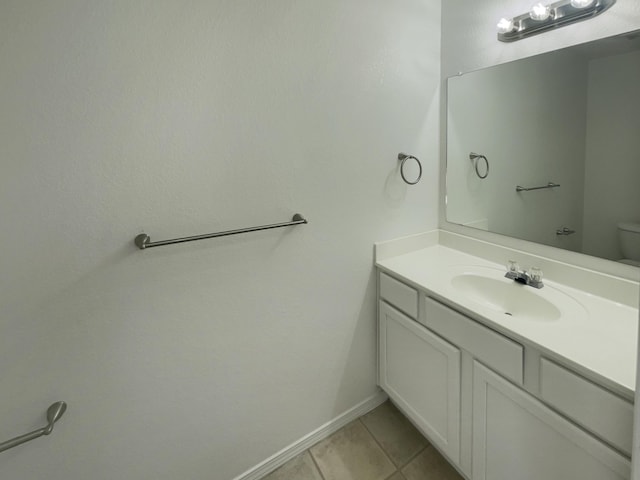 bathroom featuring baseboards, toilet, vanity, and tile patterned flooring