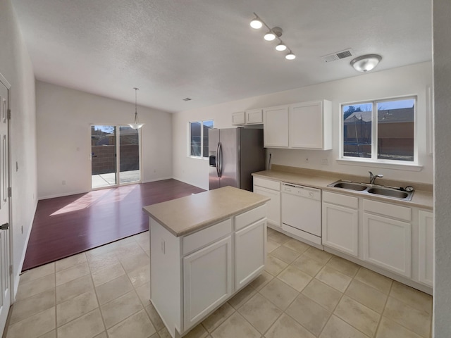 kitchen with visible vents, a sink, white cabinetry, stainless steel fridge, and dishwasher