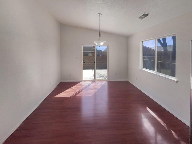 unfurnished room with lofted ceiling, wood finished floors, visible vents, and baseboards