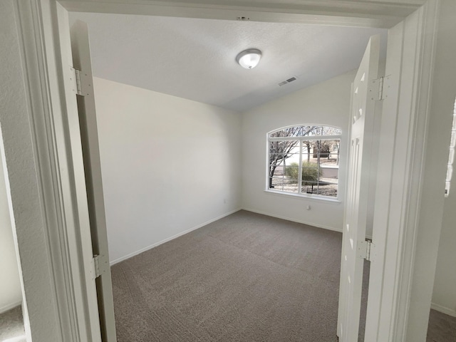 spare room featuring visible vents, baseboards, and dark carpet