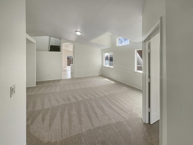 spare room with light carpet, arched walkways, and lofted ceiling