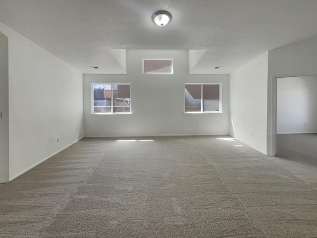 carpeted spare room with baseboards, visible vents, and a textured ceiling