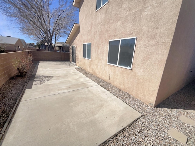 view of side of property featuring a fenced backyard, stucco siding, and a patio