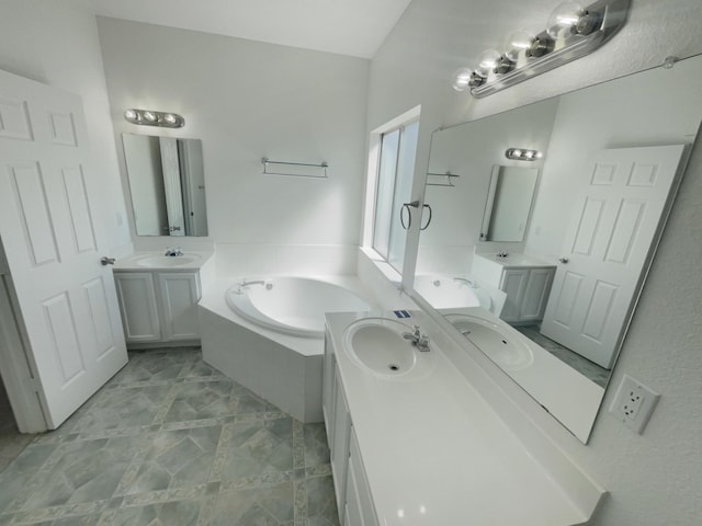 bathroom featuring a sink, a garden tub, and two vanities