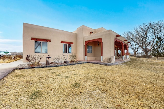 rear view of house featuring stucco siding and a lawn