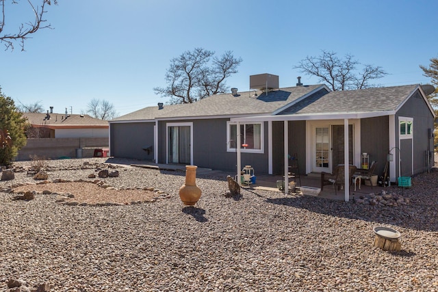 rear view of property with a patio, roof with shingles, and fence