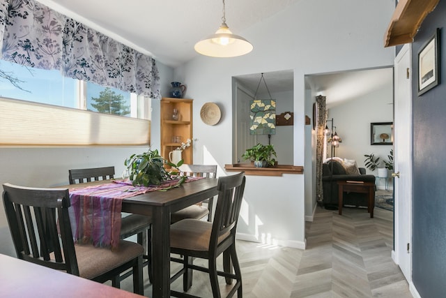 dining space featuring vaulted ceiling and baseboards