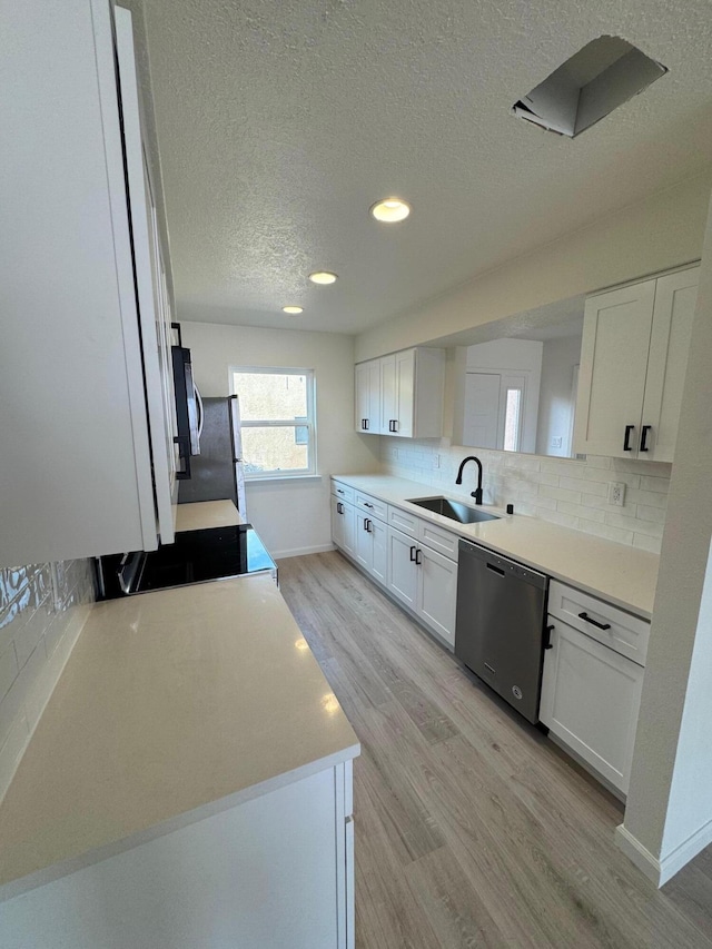 kitchen featuring tasteful backsplash, light wood-style flooring, stainless steel appliances, white cabinetry, and a sink