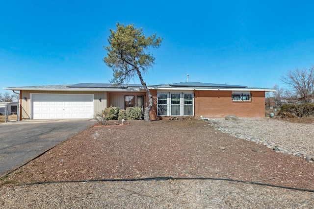 view of front of property featuring solar panels, concrete driveway, brick siding, and a garage